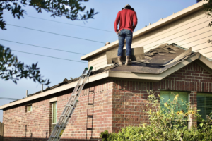 Homeowner inspecting roof for maintenance by https://unsplash.com/photos/a-man-standing-on-the-roof-of-a-house--1l0iZaM8ms