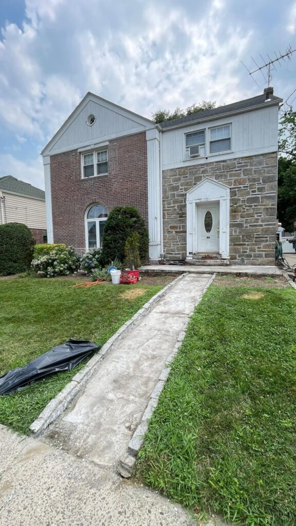 A photo showing the exterior of a home with a concrete walkway.