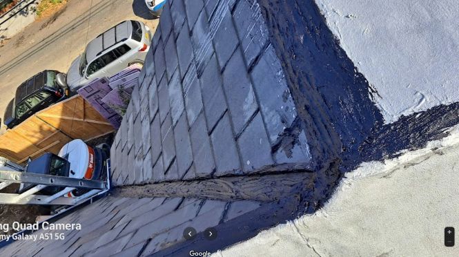 Angled view of a house roof showing aging shingles and exterior wear