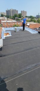 man on a roof putting reflective coat with brush
